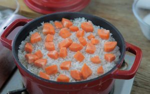 Final Steaming: Pour in the reserved mushroom soaking water. The liquid should just barely cover the surface of the rice. Sprinkle carrot dics on top.