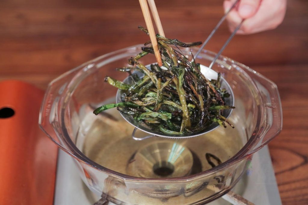 Remove Scallions Once the scallions are crispy and golden, use chopsticks or a spider strainer to remove them from the oil. Set them aside on a paper towel—do not discard them! We will use them as a topping.