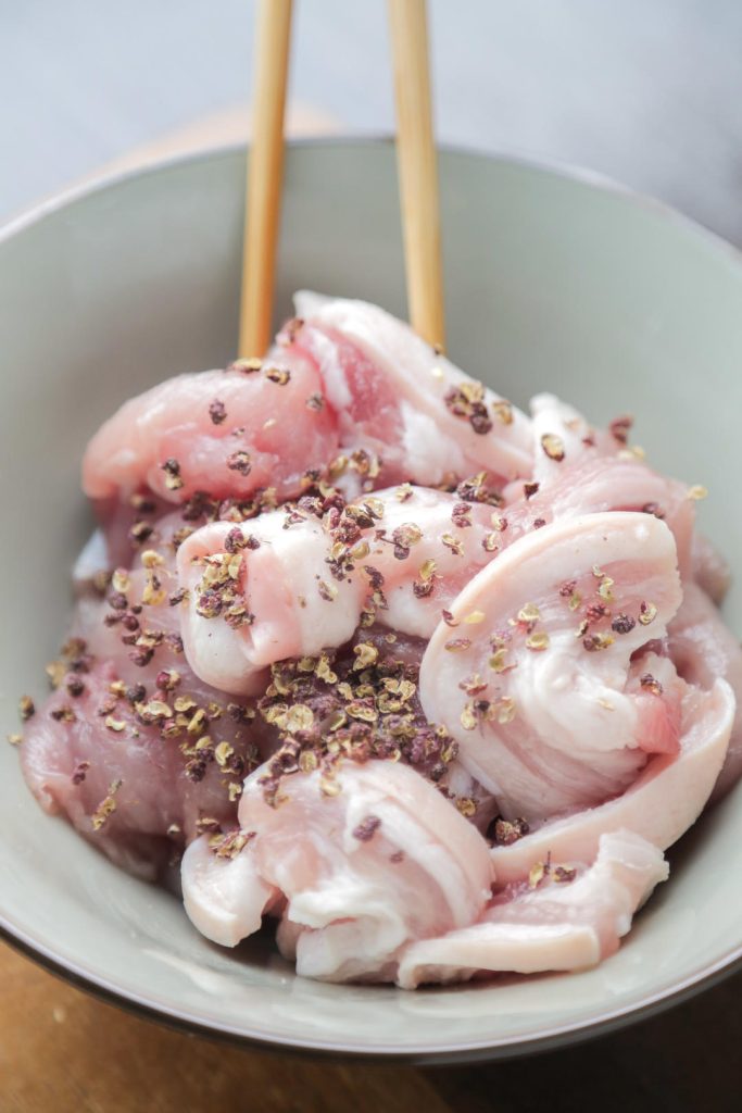Add the crushed peppercorns to the pork.