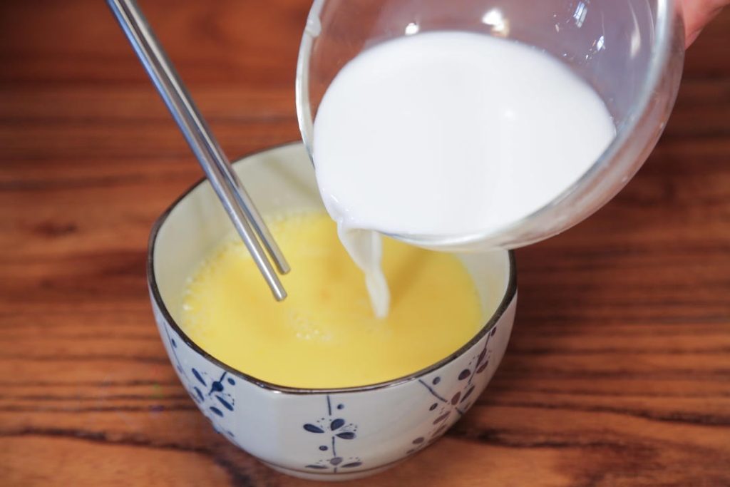 Next, pour in the cold water and the milk. The ratio here is key: roughly 1:1 liquid to egg. The milk should be about half the volume of the eggs. Whisk thoroughly to combine.
