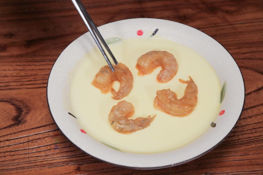 Gently place the marinated shrimp on top of the custard. They should sit on the surface without sinking. Cover the steamer lid (you don't need to put the plastic wrap back on) and steam for another 3 minutes.