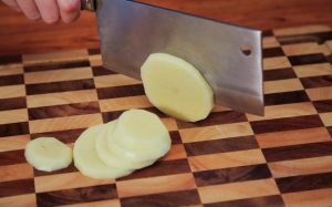 Prepare the Vegetables: Wash and peel the potato. Slice it into thick slices (about ¼ inch thick). Soak the slices in a bowl of cold water to remove excess starch; this prevents them from sticking to the pan and oxidizing. Slice the ginger. Peel the garlic cloves and leave them whole.