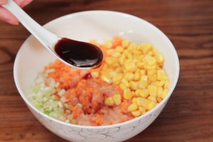 In a large mixing bowl, combine the minced chicken, diced carrots, corn kernels, and chopped scallions. Add 1 tablespoon Shaoxing wine, 1 tablespoon oyster sauce, the egg white, and white pepper.