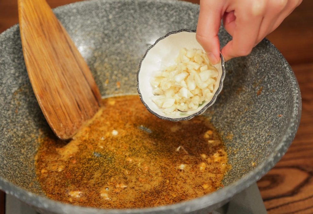 Sauté Aromatics In the same pan with the shrimp oil, add the chopped onion and minced garlic. Stir-fry until fragrant and the onion turns translucent.