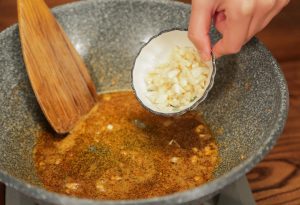 Sauté Aromatics In the same pan with the shrimp oil, add the chopped onion and minced garlic. Stir-fry until fragrant and the onion turns translucent.