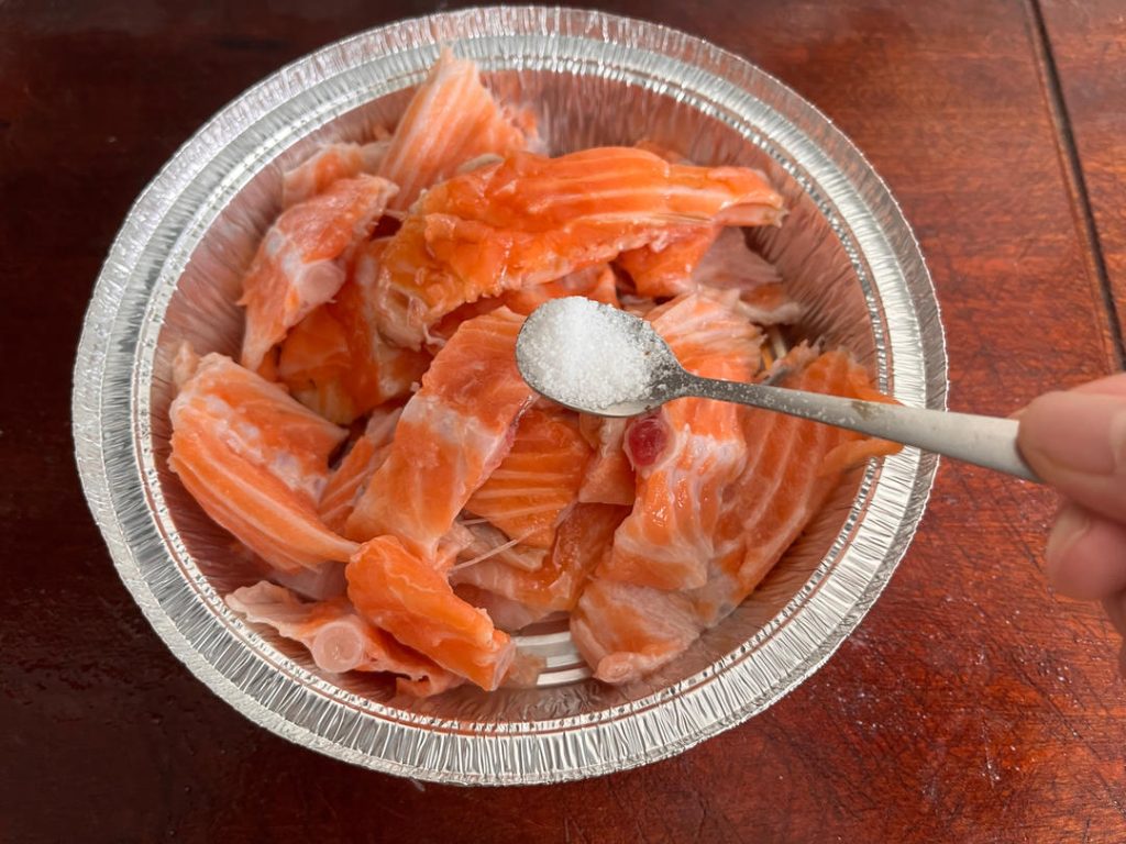Marinate Place the salmon segments in a foil tray (or a bowl). Add 2 tablespoons of Light Soy Sauce, 1 tablespoon of Shaoxing Wine, 1/2 teaspoon of Salt, and a generous grinding of black pepper. Toss well to coat. Let this sit for 15 minutes. This allows the salt to penetrate the meat and creates a brine effect.