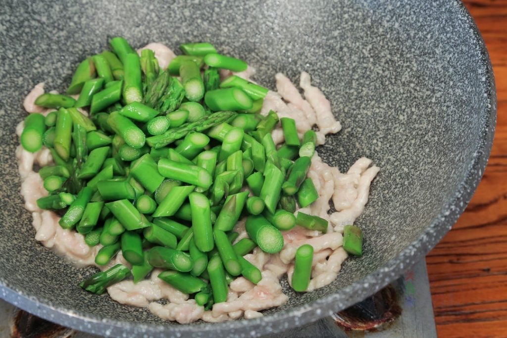 Combine: Add the blanched asparagus and carrots to the wok.