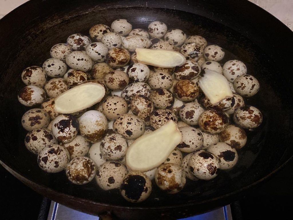 Place the rinsed quail eggs into your pot. Add the ginger slices, Shaoxing wine, and enough cold water to submerge the eggs completely. Turn the heat to your stove's lowest setting.