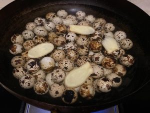 Place the rinsed quail eggs into your pot. Add the ginger slices, Shaoxing wine, and enough cold water to submerge the eggs completely. Turn the heat to your stove's lowest setting.