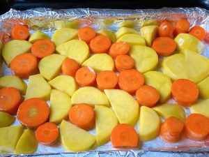Prepare the Roasting Pan: Preheat your oven to 220°C (430°F) for 10 minutes. Line your roasting pan with aluminum foil. Toss the thick slices of potato and carrot with a little oil, salt, and pepper. Spread them out evenly on the foil, making sure there are no large gaps.