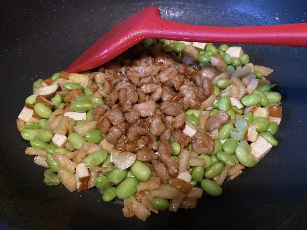 Combine the Ingredients (1 minute): Toss in the boiled soybeans and stir well. Next, return the cooked pork to the wok. We add the pork at the end because it is already cooked; exposing it to prolonged wok heat will make it tough.