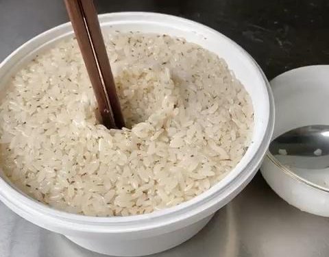 Pack and Shape (2 minutes): Transfer the mixture into your sterilized fermentation container. Press it down lightly to flatten the surface. Tip: Dip your spoon in cool boiled water so the sticky rice doesn't cling to it. Use your finger or a chopstick to poke a hole straight down the middle of the rice. This hole acts as a window to observe the fermentation liquid gathering.