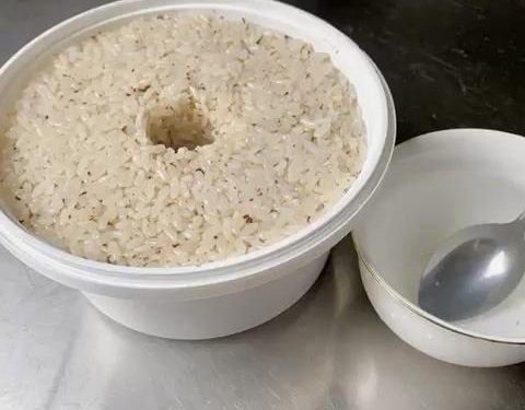 Pack and Shape (2 minutes): Transfer the mixture into your sterilized fermentation container. Press it down lightly to flatten the surface. Tip: Dip your spoon in cool boiled water so the sticky rice doesn't cling to it. Use your finger or a chopstick to poke a hole straight down the middle of the rice. This hole acts as a window to observe the fermentation liquid gathering.