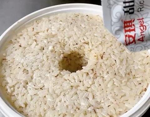 Pack and Shape (2 minutes): Transfer the mixture into your sterilized fermentation container. Press it down lightly to flatten the surface. Tip: Dip your spoon in cool boiled water so the sticky rice doesn't cling to it. Use your finger or a chopstick to poke a hole straight down the middle of the rice. This hole acts as a window to observe the fermentation liquid gathering.