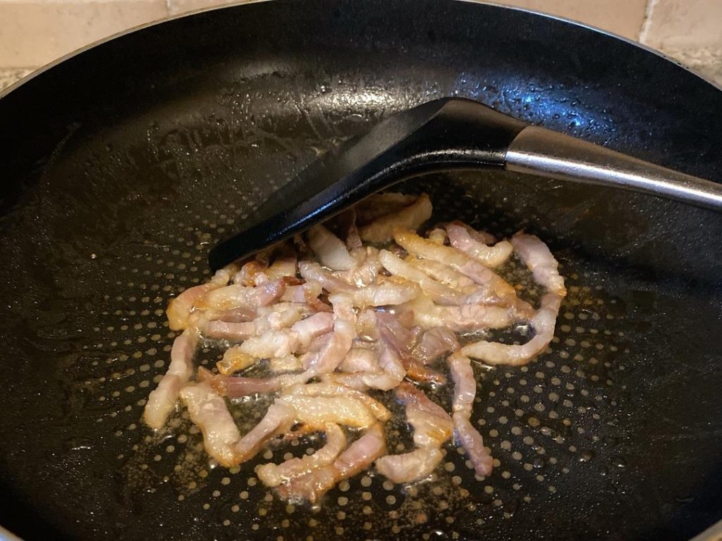 Render the Pork Fat (2–3 minutes): Place your wok over medium-low heat. Add 1 tablespoon of oil and the sliced cured pork. Stir-fry slowly until the pork turns translucent and releases its fragrant fat into the wok.