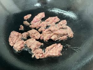 Render the Beef (No Oil Needed!) Wipe the wok clean. Do not add oil. Add the beef patties (or ground beef) to the cold or warm pan. Turn heat to medium-high. Break the beef up with your spatula.