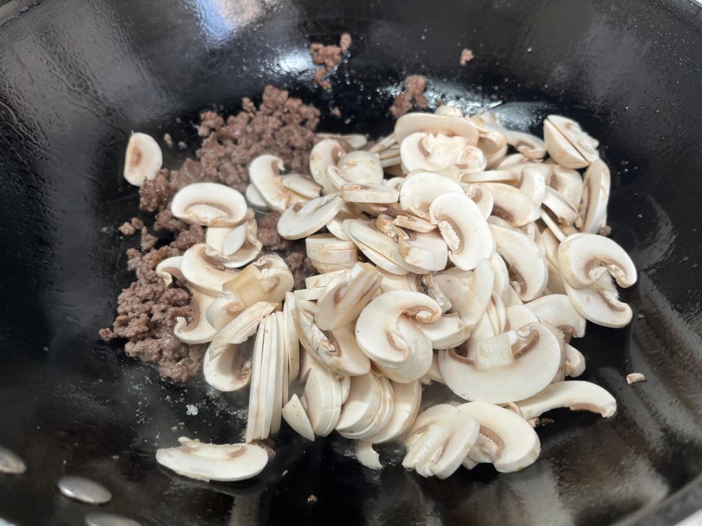 Cook Mushrooms and Remove Moisture Once the beef is browned and has released its fat, add the sliced mushrooms. Stir-fry them together. Add the Light Soy Sauce and Salt now.