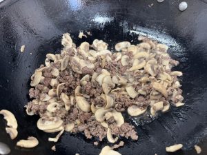 Cook Mushrooms and Remove Moisture Once the beef is browned and has released its fat, add the sliced mushrooms. Stir-fry them together. Add the Light Soy Sauce and Salt now.