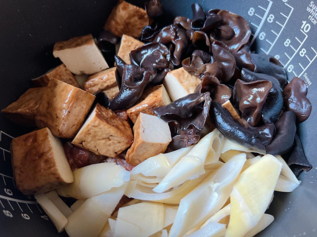 Add the Ingredients: Neatly layer the marinated pork ribs over the spices. Next, add the quartered thick dried tofu, wood ear mushrooms, and bamboo shoots on top.