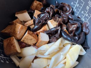 Add the Ingredients: Neatly layer the marinated pork ribs over the spices. Next, add the quartered thick dried tofu, wood ear mushrooms, and bamboo shoots on top.
