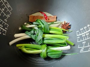 Layer the Aromatics: Place the scallion knots, cassia bark, star anise, bay leaves, and chilies at the very bottom of your rice cooker pot. Purpose: This prevents the meat from sticking to the bottom and infuses the cooking liquid from the base up.