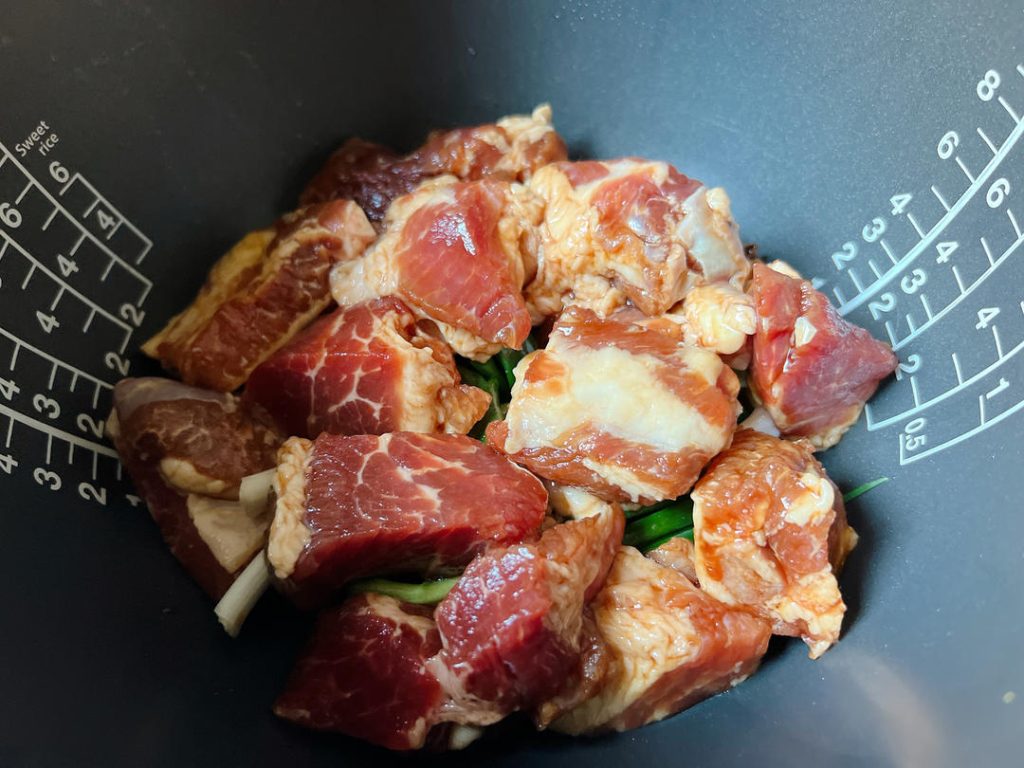 Add the Ingredients: Neatly layer the marinated pork ribs over the spices. Next, add the quartered thick dried tofu, wood ear mushrooms, and bamboo shoots on top.
