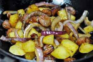 Render the Sausage Add the sliced Chinese sausage and potato cubes to the pan. Stir-fry for 2-3 minutes until the sausage turns transparent and releases its red oil, and the potatoes develop a slight crust.