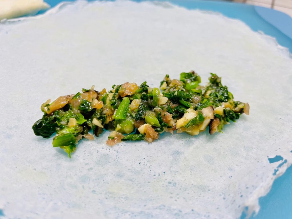 Wrap the rolls: Place a wrapper on a flat surface like a diamond. Spoon 2 tablespoons of filling near the bottom corner. Roll halfway up, fold the left and right corners tightly into the center, and continue rolling. Smear a little flour-water paste on the top corner to seal it shut.