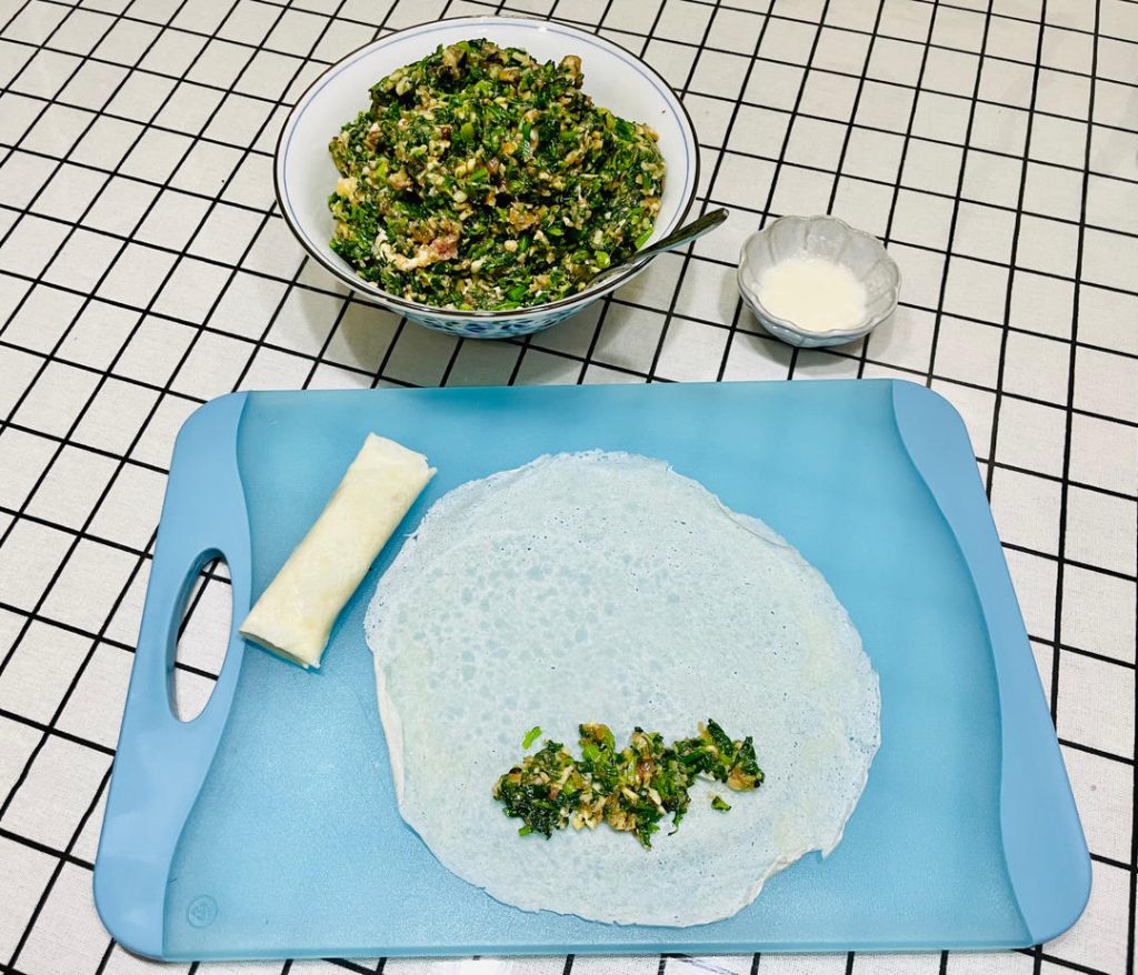 Wrap the rolls: Place a wrapper on a flat surface like a diamond. Spoon 2 tablespoons of filling near the bottom corner. Roll halfway up, fold the left and right corners tightly into the center, and continue rolling. Smear a little flour-water paste on the top corner to seal it shut.
