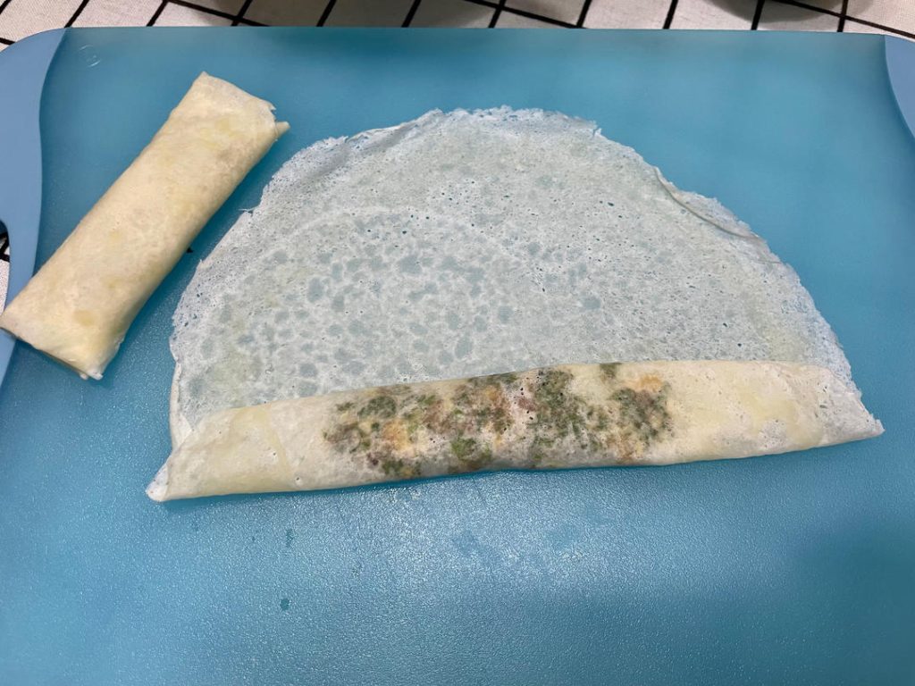 Wrap the rolls: Place a wrapper on a flat surface like a diamond. Spoon 2 tablespoons of filling near the bottom corner. Roll halfway up, fold the left and right corners tightly into the center, and continue rolling. Smear a little flour-water paste on the top corner to seal it shut.