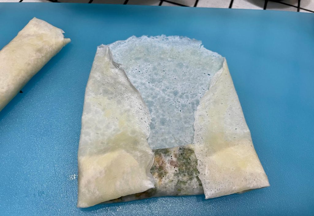 Wrap the rolls: Place a wrapper on a flat surface like a diamond. Spoon 2 tablespoons of filling near the bottom corner. Roll halfway up, fold the left and right corners tightly into the center, and continue rolling. Smear a little flour-water paste on the top corner to seal it shut.