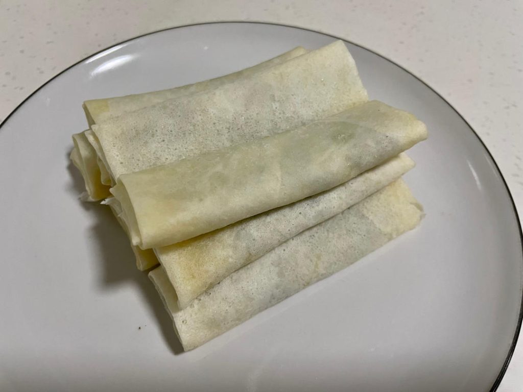 Wrap the rolls: Place a wrapper on a flat surface like a diamond. Spoon 2 tablespoons of filling near the bottom corner. Roll halfway up, fold the left and right corners tightly into the center, and continue rolling. Smear a little flour-water paste on the top corner to seal it shut.