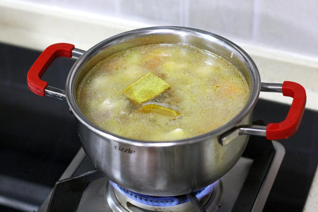 Combine and Simmer Return the semi-cooked chicken and onions to the pot. Stir to combine everything evenly. Pour in enough water to just cover the ingredients. Add the curry blocks, bird's eye chilies, and the scallion knot.
