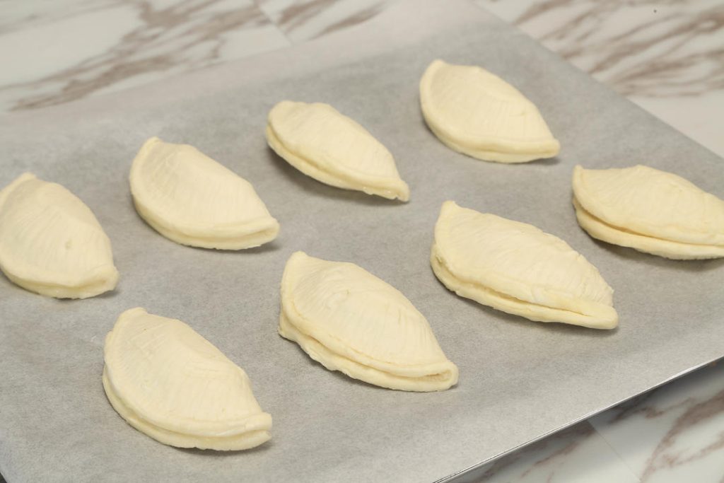 Take a tart shell and flatten it slightly with your palm. Place a spoonful of the cooked durian paste in the center. Do not be greedy! Overfilling is the #1 cause of leakage.