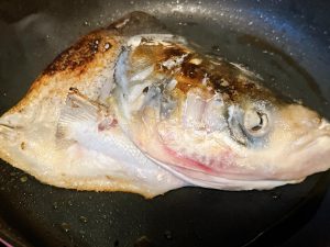 Sear the Fish Head Heat your wok over medium-high heat until lightly smoking. Add the cooking oil and swirl to coat the bottom. Carefully place the fish head cut-side down into the wok. Fry undisturbed for 3 to 4 minutes until a golden-brown crust forms.