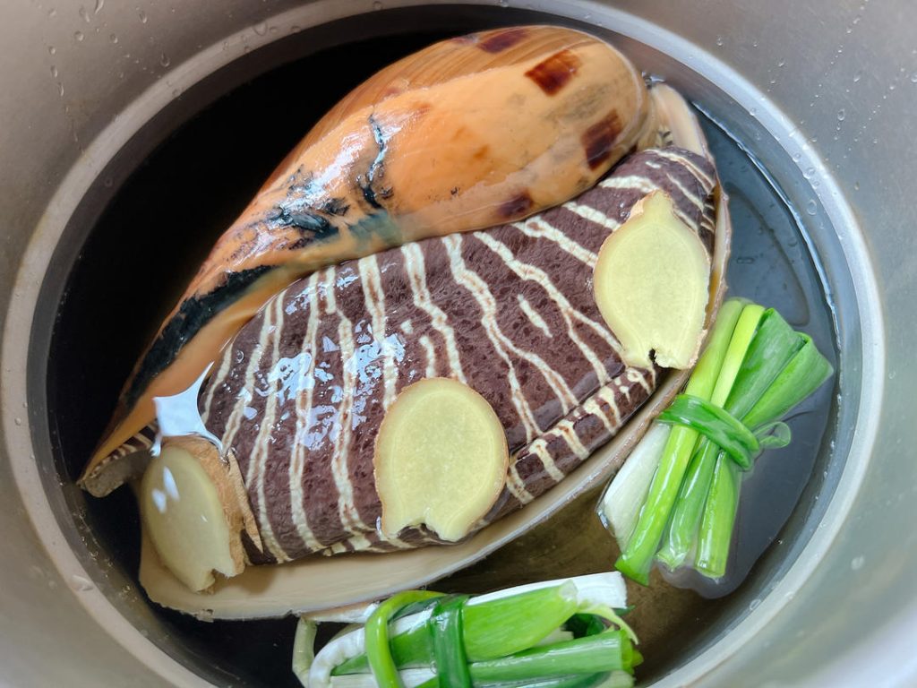 Add Aromatics: Toss in the ginger slices, scallion knots, and Shaoxing wine. 3. Add Water: Pour in fresh water until it reaches exactly halfway up the side of the shell. Do not fully submerge it.