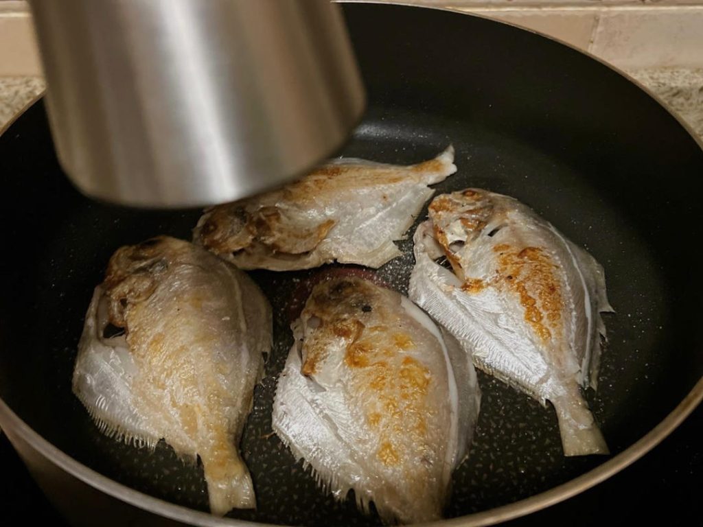 Season and Flip: Sprinkle a pinch of sea salt evenly over the exposed side of the fish. Carefully flip the fish using a wide spatula. Immediately sprinkle salt on the newly flipped, crispy side.