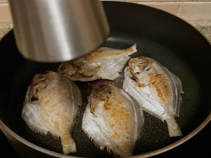 Season and Flip: Sprinkle a pinch of sea salt evenly over the exposed side of the fish. Carefully flip the fish using a wide spatula. Immediately sprinkle salt on the newly flipped, crispy side.