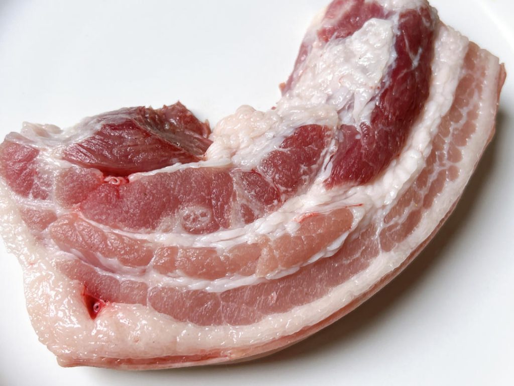 Before you begin, gather your flour and the pork. Place the pork in a large mixing bowl. Add the flour and a tiny splash of water to form a loose paste on the surface of the meat.