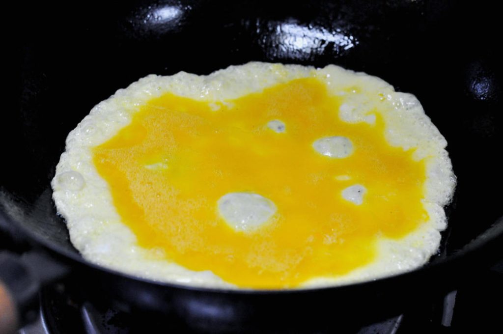 Cook the Eggs Heat a wok or non-stick skillet over medium-high heat. Add 1 tablespoon of oil. When the oil is shimmering, pour in the beaten eggs.