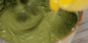 Take one-third of the stiff egg whites and add them to the green yolk batter. Using a spatula, gently fold it in to lighten the batter.
