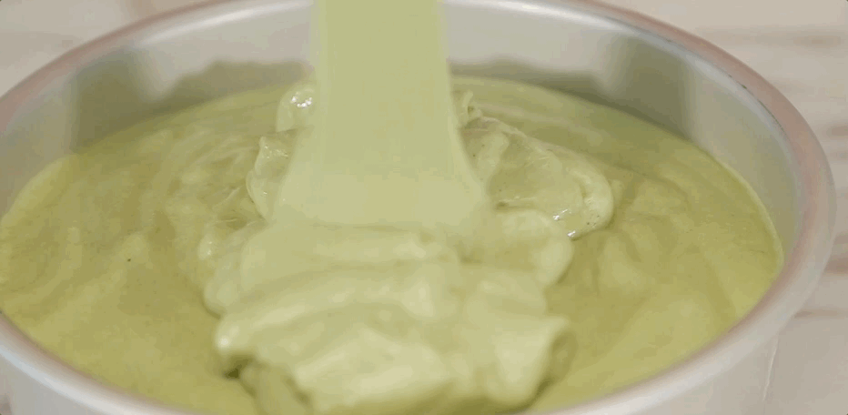 Take one-third of the stiff egg whites and add them to the green yolk batter. Using a spatula, gently fold it in to lighten the batter.