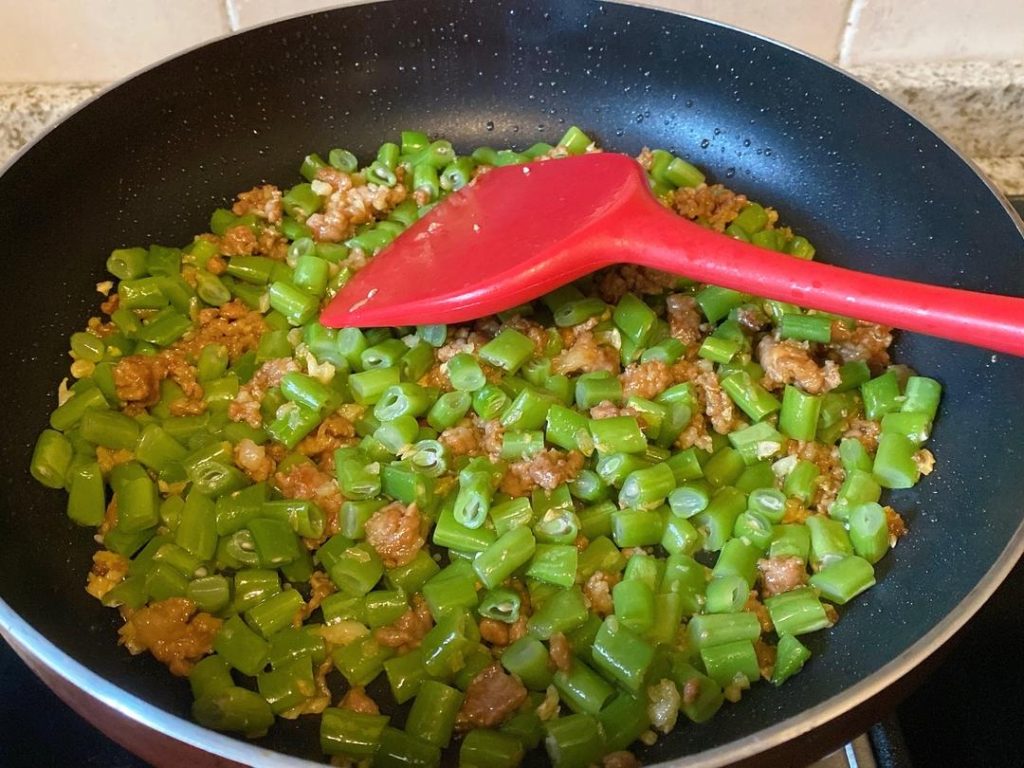 Combine and Season: Dump the chopped green beans into the wok. Toss vigorously for 30 seconds to combine with the pork. Add the remaining 1/2 tbsp of oyster sauce and 1/4 tsp of salt.