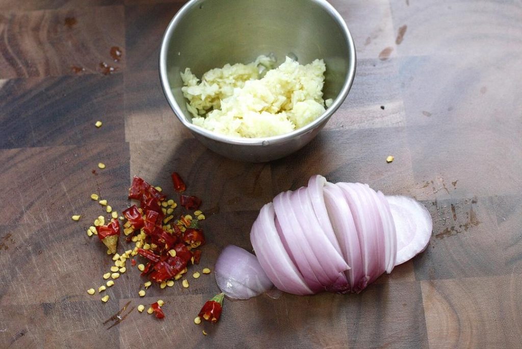 Create the Aromatic Bed Place your cast iron pot over medium heat. Add the neutral oil. Once the oil shimmers, add the smashed garlic and sliced onions. Sauté for 1-2 minutes until the onions are fragrant and slightly softened, but not browned. Spread them out evenly to cover the entire bottom of the pot.