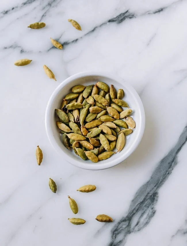Close-up of split green cardamom pods revealing dark brown aromatic seeds.