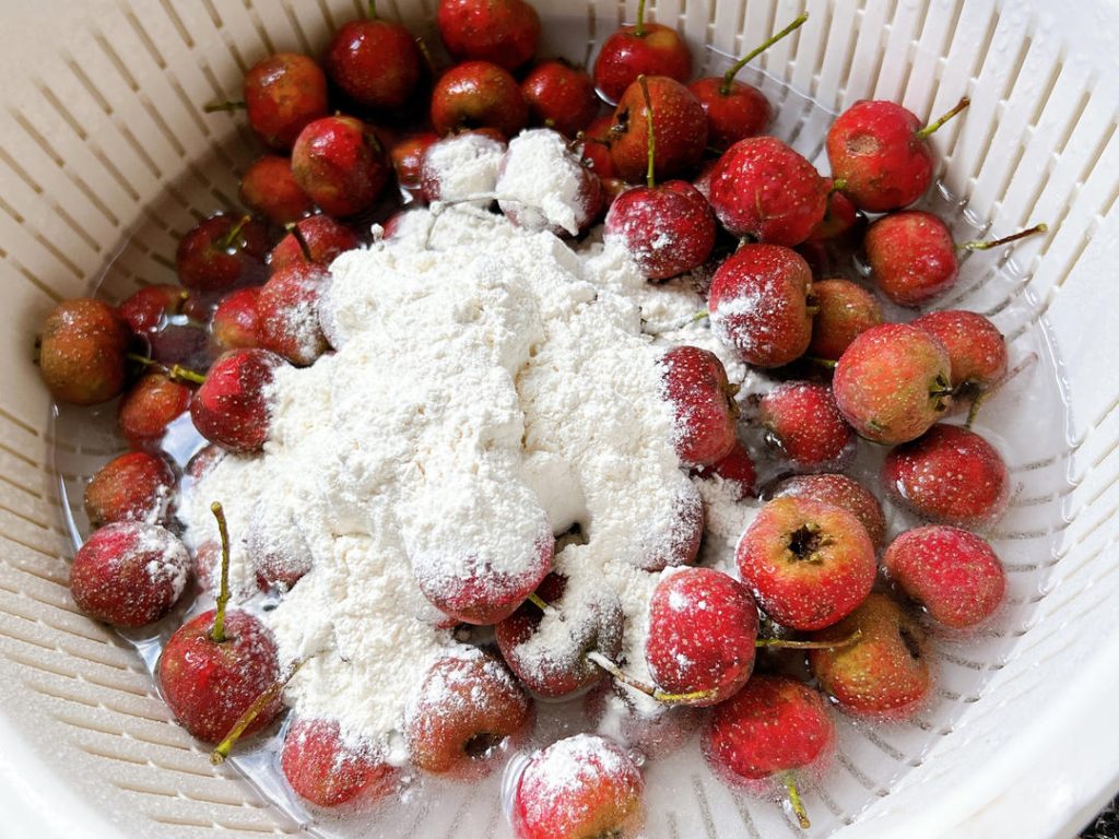 First, add your berries to a large bowl of water with 2 tablespoons of flour. Rub the berries continuously in this flour-water mixture. You will quickly notice the water turning murky as the flour lifts away the dirt. Rinse them thoroughly under cold running water until the water runs clear.