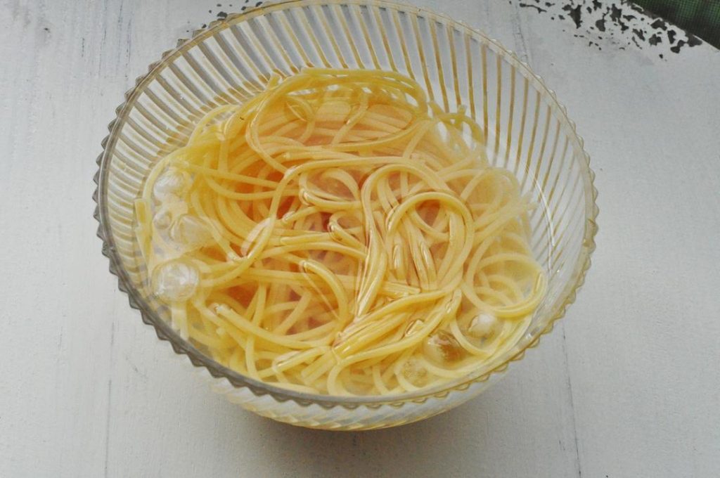 Cook and Shock the Pasta Boil the spaghetti in salted water for 5-10 minutes (follow package instructions for al dente). Crucial Step: Once cooked, immediately drain and plunge the noodles into a bowl of ice water. Drain again after 1 minute and toss with a teaspoon of oil to prevent sticking.