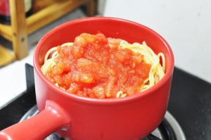 Combine and Simmer Spread the stir-fried ingredients to the sides of the wok. Add the cooked spaghetti and the reserved fresh tomato puree into the center. Add the ketchup.