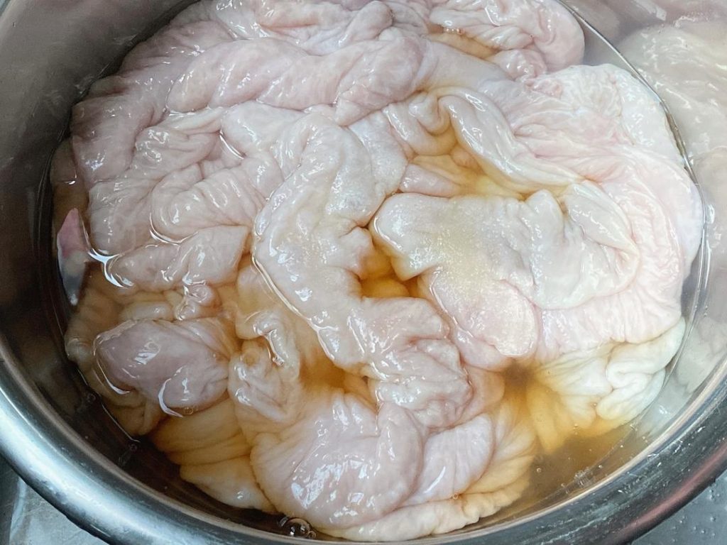 Drain the intestines. Add 3 tablespoons of salt and 3 tablespoons of Shaoxing wine. Knead vigorously one last time. This combination acts as a powerful deodorizer. Rinse thoroughly until the water is completely crystal clear.