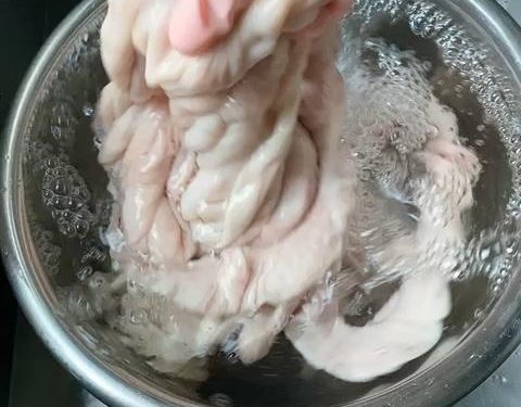 Drain the intestines. Add 3 tablespoons of salt and 3 tablespoons of Shaoxing wine. Knead vigorously one last time. This combination acts as a powerful deodorizer. Rinse thoroughly until the water is completely crystal clear.